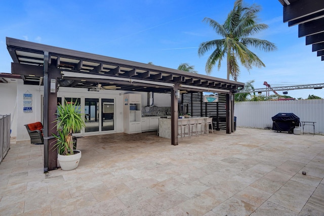 view of patio featuring ceiling fan, a bar, and grilling area