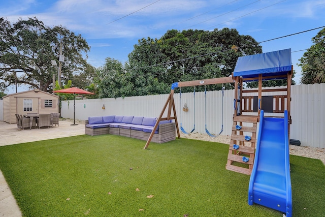 view of jungle gym with a lawn, a patio area, and a storage shed