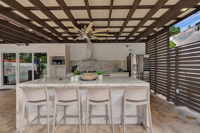 kitchen featuring backsplash, stainless steel fridge, a breakfast bar, and light stone counters