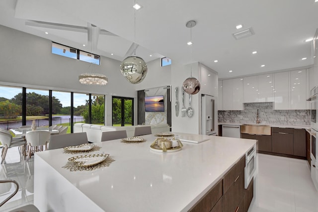 kitchen with white cabinetry, tasteful backsplash, dark brown cabinets, stainless steel dishwasher, and sink