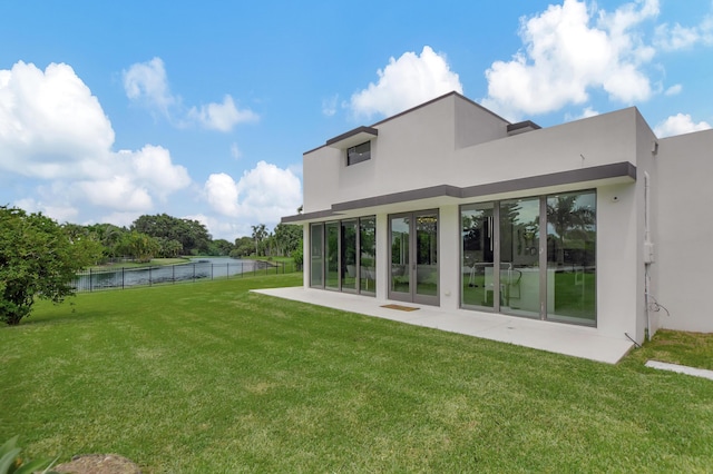 rear view of house featuring a lawn, a water view, and a patio area