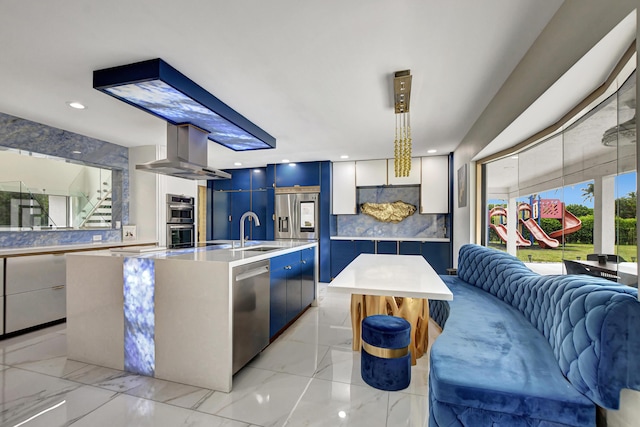 kitchen featuring sink, white cabinetry, a kitchen island with sink, appliances with stainless steel finishes, and wall chimney exhaust hood