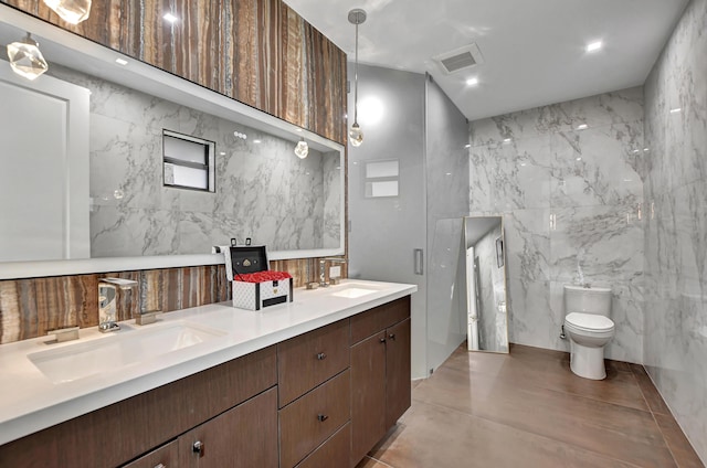 bathroom featuring toilet, vanity, and tile walls