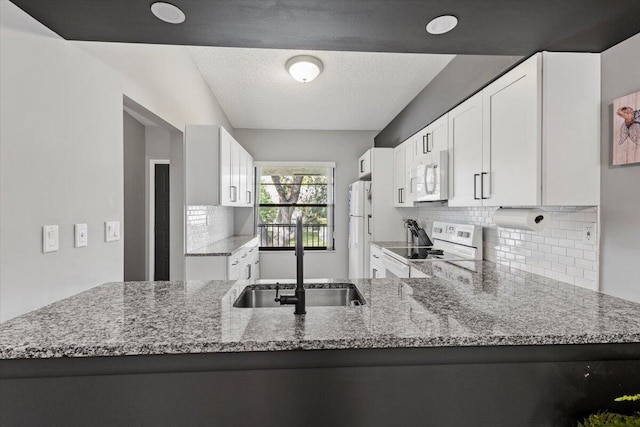 kitchen with white cabinetry, sink, light stone counters, kitchen peninsula, and white appliances