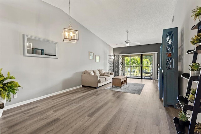 living room featuring wood-type flooring, a textured ceiling, vaulted ceiling, and ceiling fan