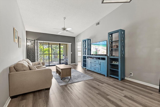 living room with hardwood / wood-style floors, a textured ceiling, ceiling fan, and lofted ceiling