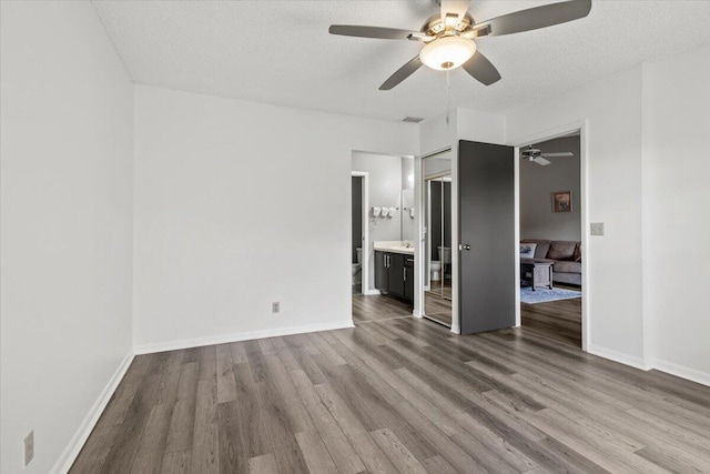 unfurnished bedroom featuring a textured ceiling, a closet, ensuite bath, and ceiling fan