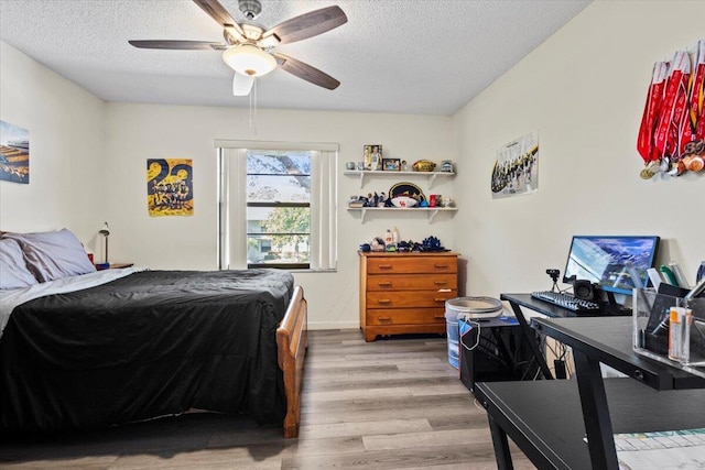 bedroom with a textured ceiling, light hardwood / wood-style flooring, and ceiling fan