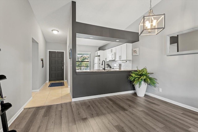 entryway with a notable chandelier, light wood-type flooring, sink, and vaulted ceiling