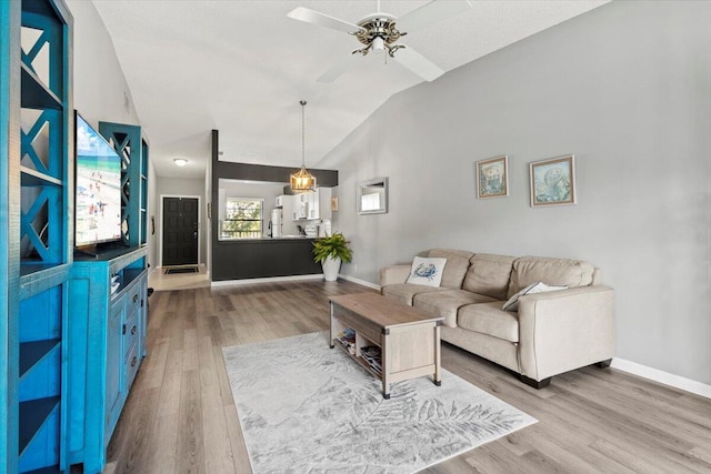 living room featuring hardwood / wood-style flooring, ceiling fan, and vaulted ceiling