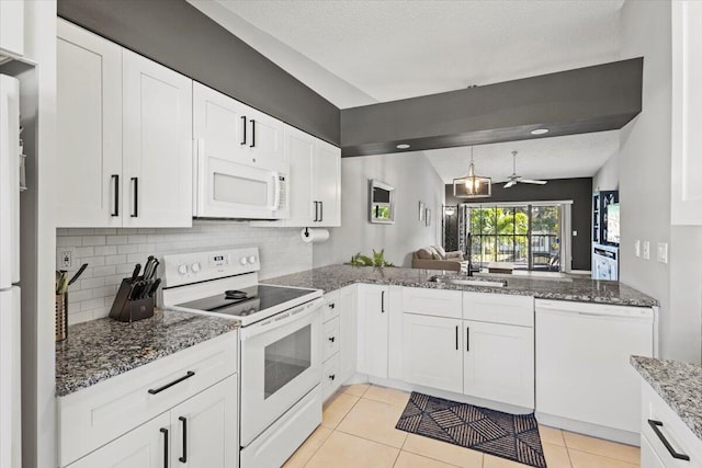 kitchen featuring white appliances, lofted ceiling, white cabinets, sink, and ceiling fan