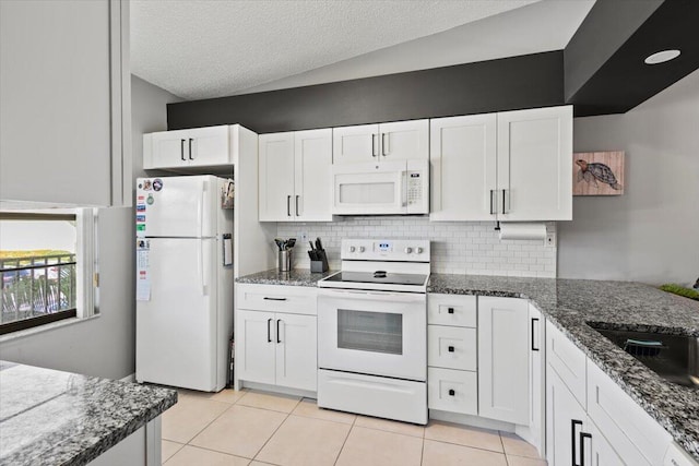 kitchen featuring light tile patterned floors, white appliances, white cabinetry, and lofted ceiling