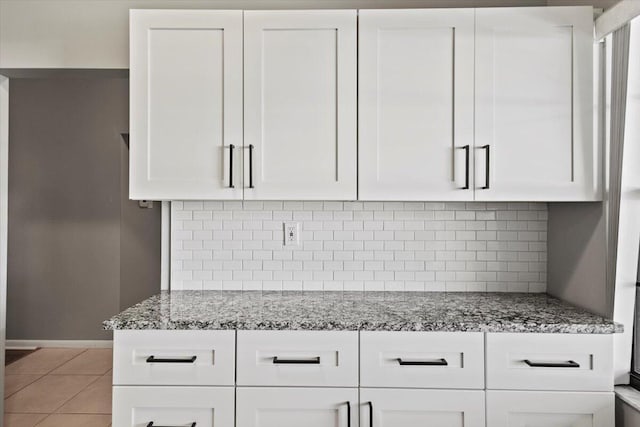 kitchen with white cabinets, decorative backsplash, light stone countertops, and light tile patterned floors