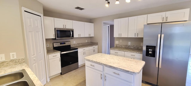 kitchen featuring white cabinets, a center island, light tile patterned floors, and stainless steel appliances