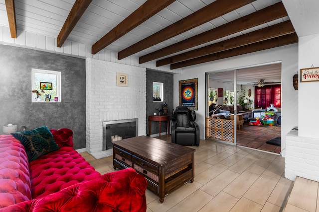 living room featuring beamed ceiling, a brick fireplace, and ceiling fan