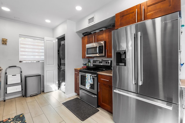 kitchen featuring stacked washer / dryer, appliances with stainless steel finishes, and dark stone counters