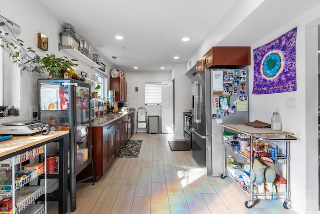 kitchen with sink, light stone countertops, light hardwood / wood-style floors, and appliances with stainless steel finishes