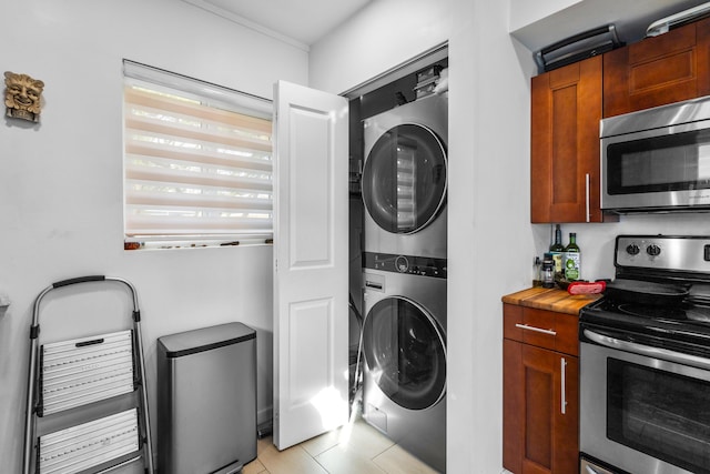 clothes washing area featuring stacked washer / drying machine and light tile patterned floors