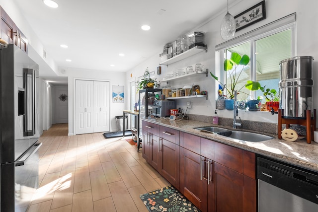 kitchen featuring stainless steel appliances, sink, pendant lighting, and light stone counters