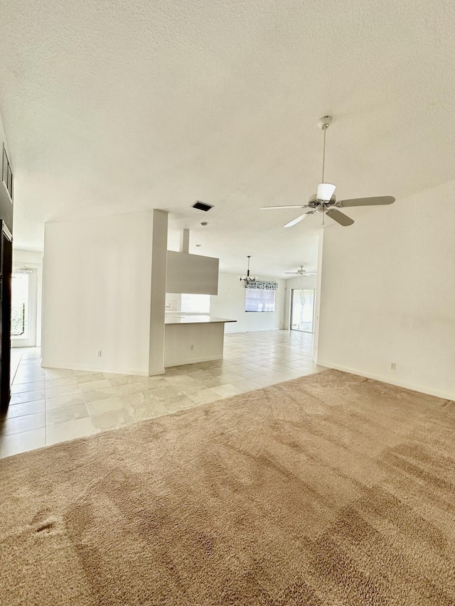 unfurnished living room featuring ceiling fan, light colored carpet, and a textured ceiling