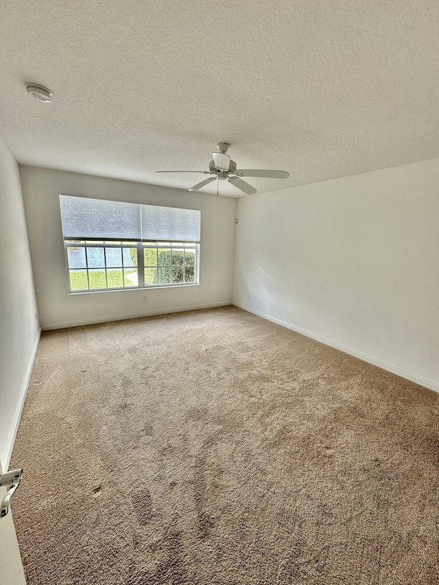 empty room featuring ceiling fan, carpet floors, and a textured ceiling