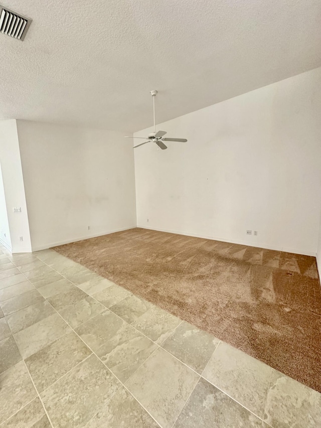 carpeted spare room featuring ceiling fan and a textured ceiling