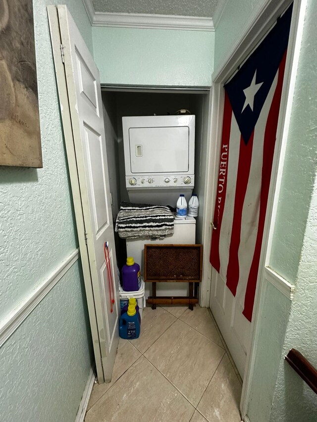 interior space featuring crown molding, light tile patterned flooring, and stacked washing maching and dryer