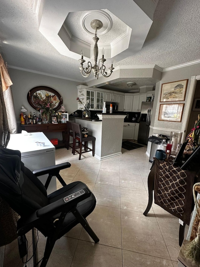 dining space with a raised ceiling, ornamental molding, and a chandelier