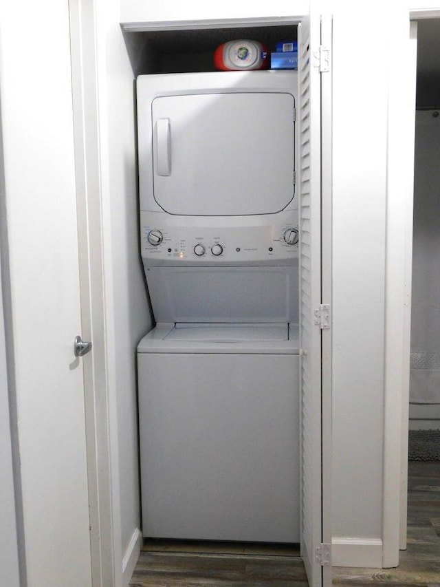 laundry area featuring stacked washer and dryer and dark hardwood / wood-style flooring