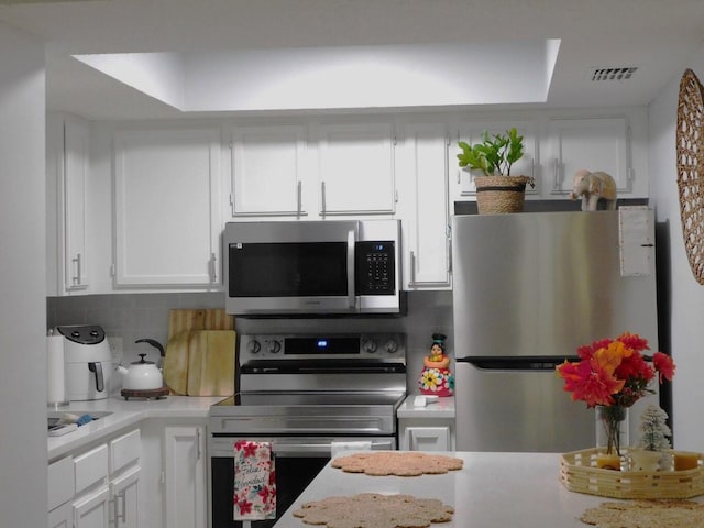 kitchen featuring backsplash, stainless steel appliances, and white cabinets