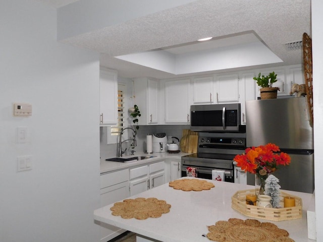 kitchen featuring tasteful backsplash, white cabinetry, appliances with stainless steel finishes, and sink