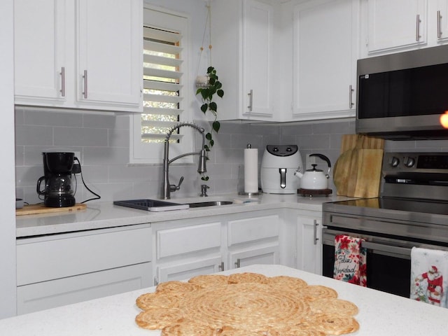 kitchen featuring tasteful backsplash, stainless steel appliances, sink, and white cabinets