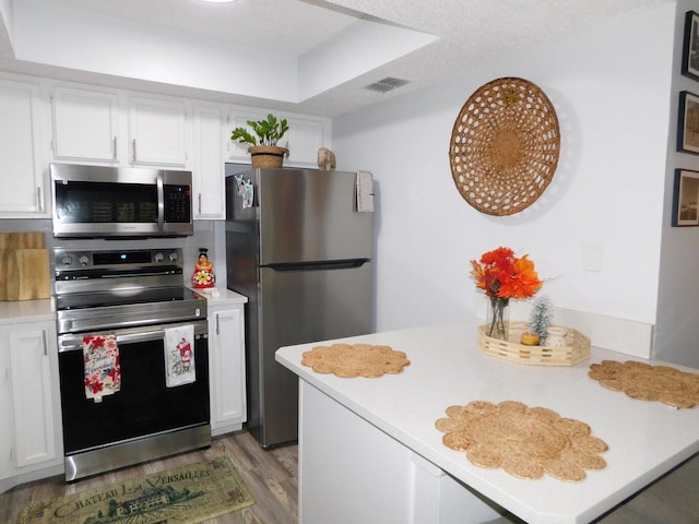 kitchen with stainless steel appliances, white cabinetry, kitchen peninsula, and light hardwood / wood-style flooring