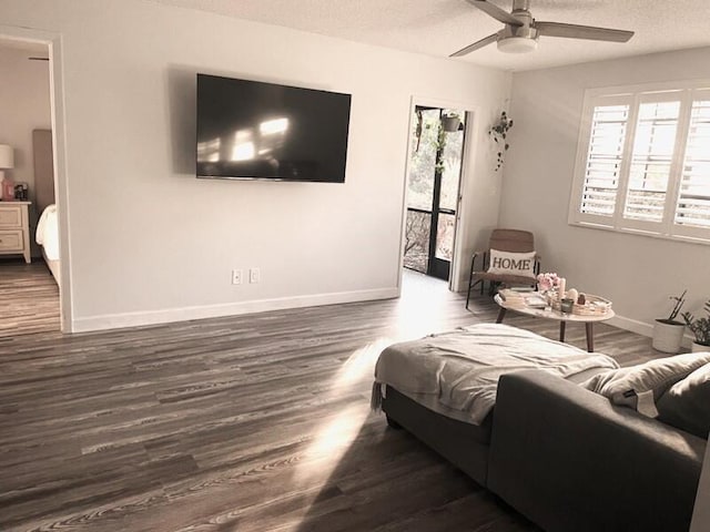 living room with ceiling fan, dark hardwood / wood-style floors, and a textured ceiling