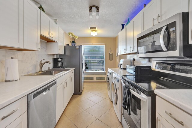 kitchen featuring white cabinets, sink, light tile patterned floors, and stainless steel appliances