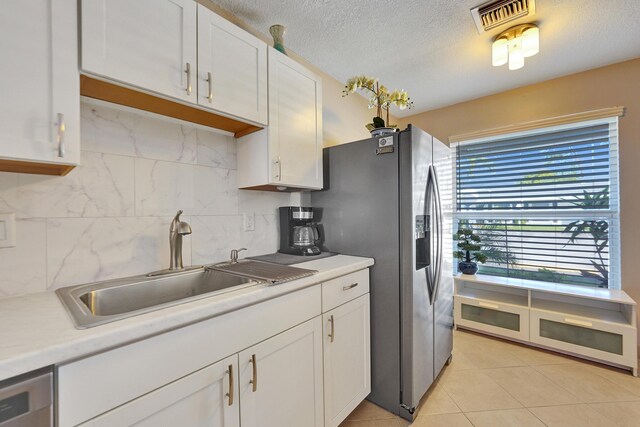 kitchen with decorative backsplash, sink, white cabinets, and light tile patterned floors