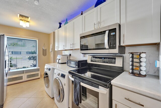 kitchen featuring white cabinets, independent washer and dryer, a textured ceiling, light tile patterned flooring, and stainless steel appliances