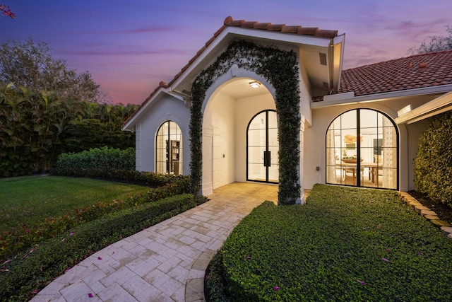 exterior entry at dusk featuring a lawn