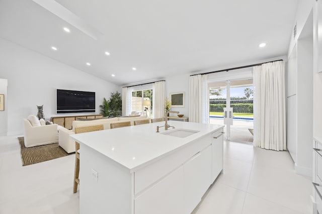 kitchen featuring sink, an island with sink, a wealth of natural light, and white cabinetry