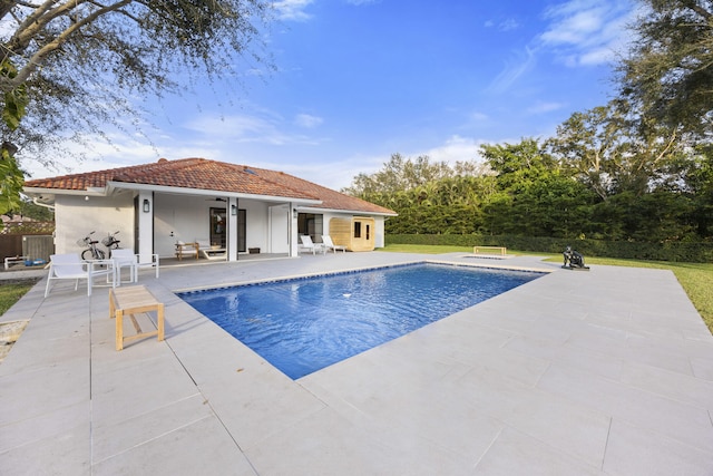 view of pool with a patio, ceiling fan, a hot tub, and an outdoor structure