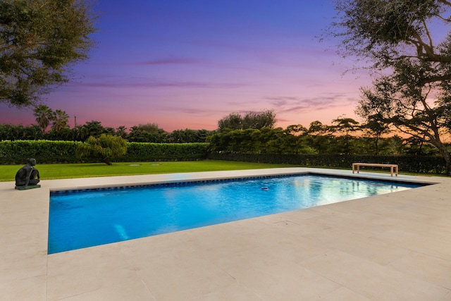 pool at dusk with a lawn and a patio area