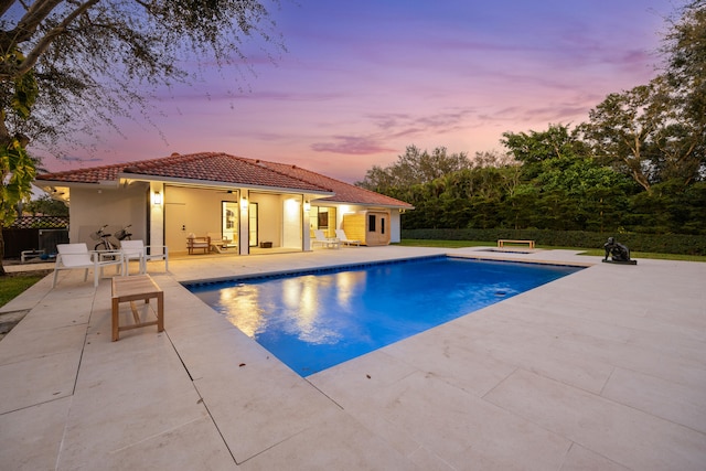 pool at dusk with an outbuilding and a patio