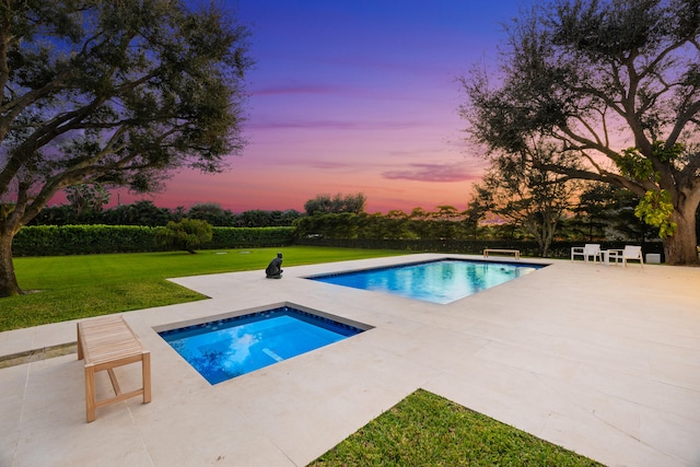 pool at dusk with a patio, a yard, and a jacuzzi