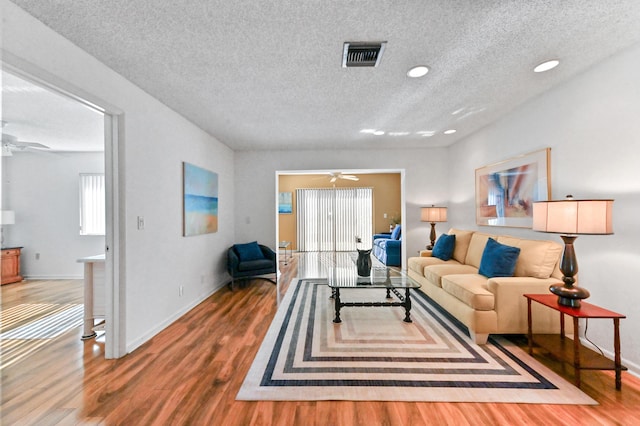 living room with a textured ceiling, hardwood / wood-style flooring, and ceiling fan