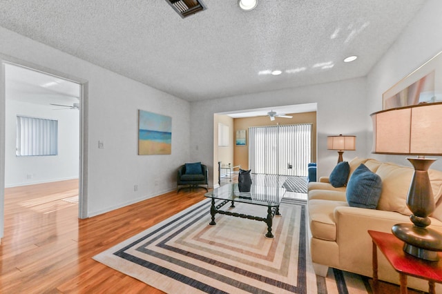 living room featuring hardwood / wood-style floors, a textured ceiling, and ceiling fan