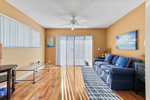 living room with ceiling fan, wood-type flooring, and a textured ceiling