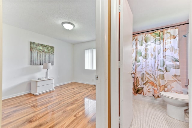 bathroom with hardwood / wood-style flooring, toilet, a textured ceiling, and shower / tub combo