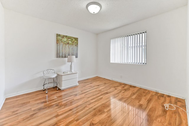 unfurnished room with a textured ceiling and light wood-type flooring