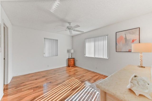 living area featuring ceiling fan, wood-type flooring, and a textured ceiling