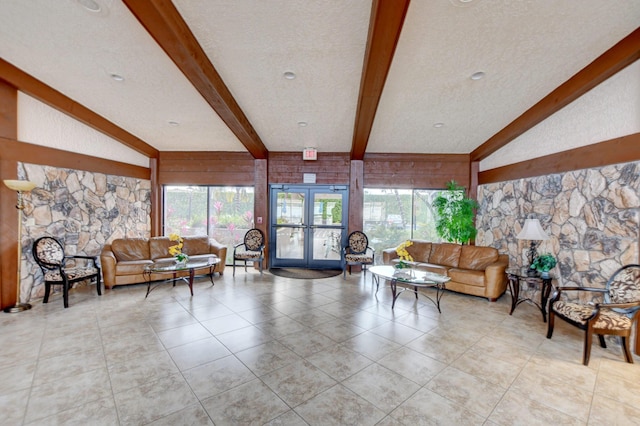 tiled living room with plenty of natural light, wood walls, a textured ceiling, and french doors